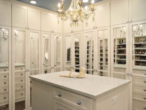 A white walk-in closet with mirrors and chandelier