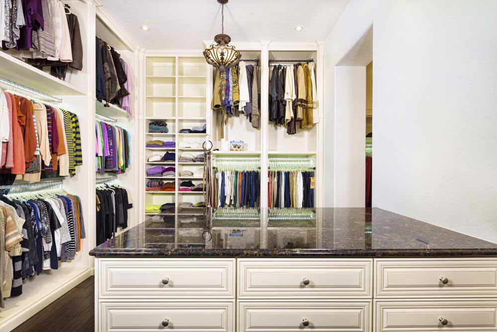 A neatly arranged custom closet with dresser island.